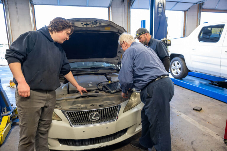 Two men working on a car in a garage.