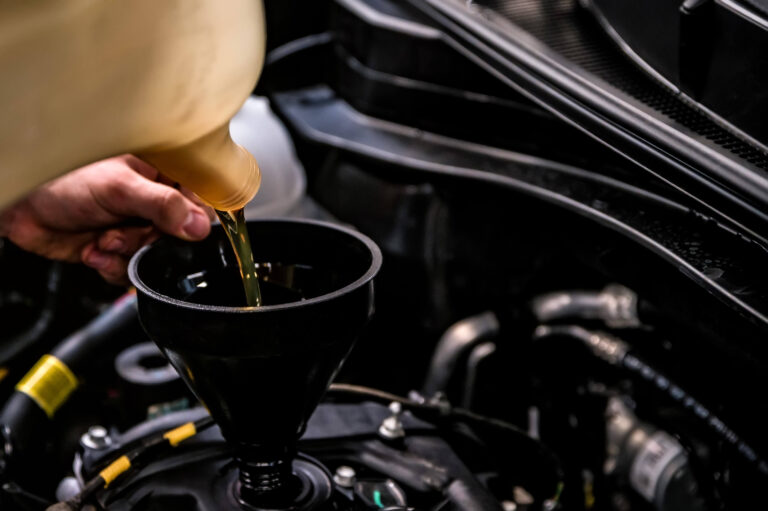 A man pouring oil into a car engine.