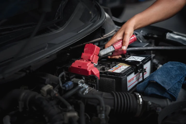 A person using a wrench to work on a car battery.