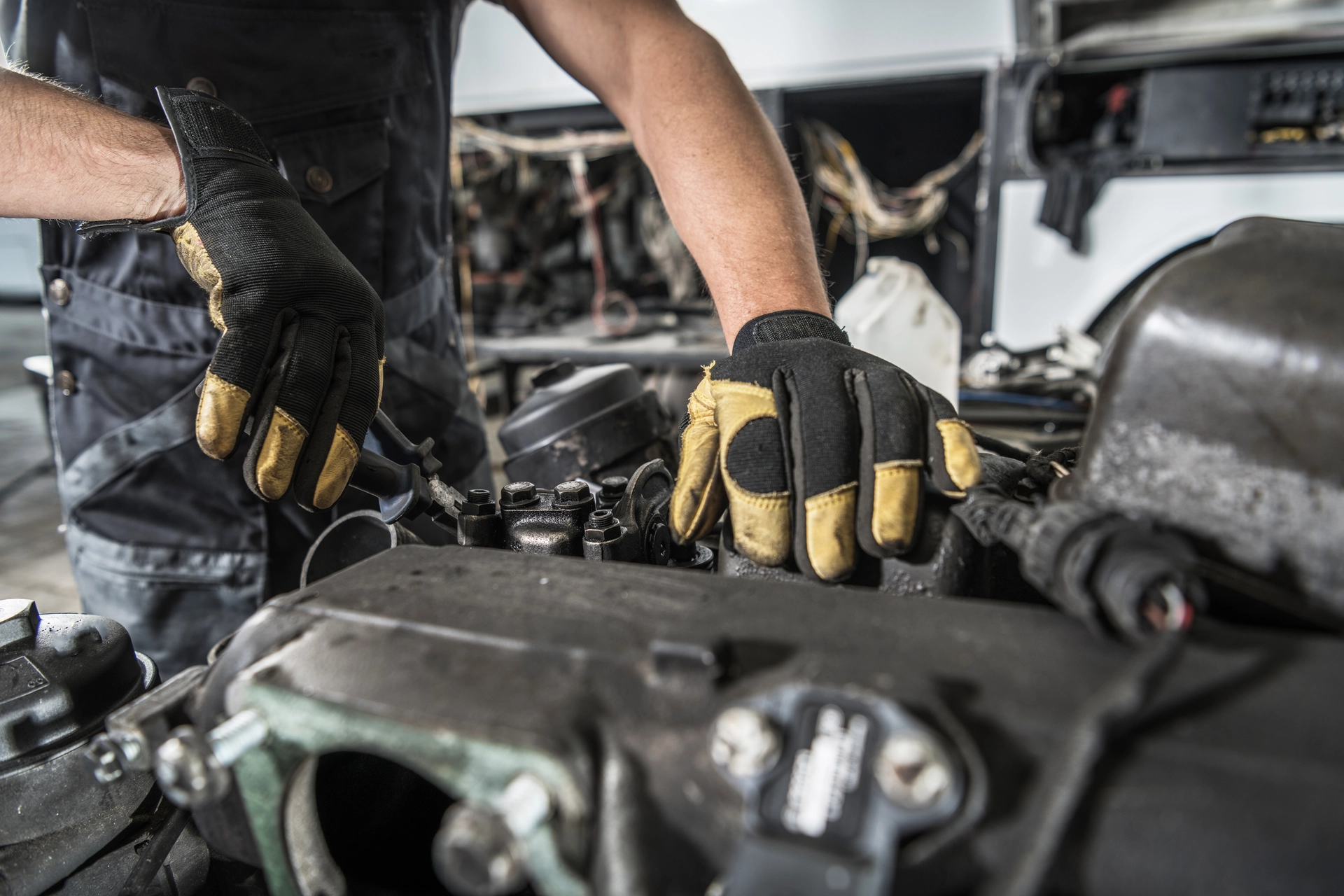 Mechanic working on a car engine with focus on hands and tools.