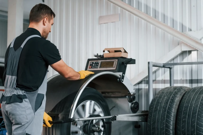 Mechanic balancing a car wheel with a machine at a service station.